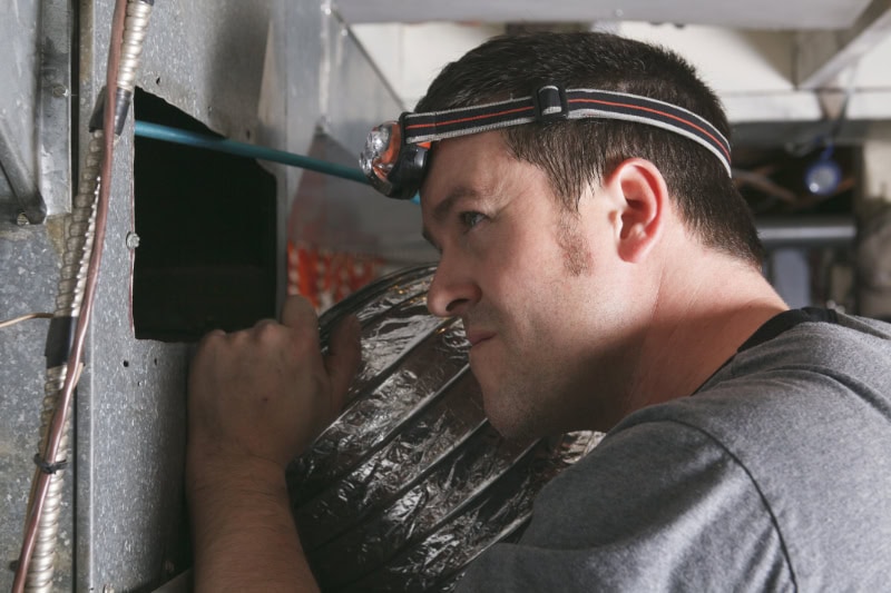 HVAC Technician performing maintenance on a furnace.